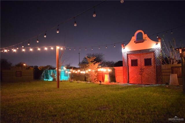 yard at twilight with an outbuilding and fence