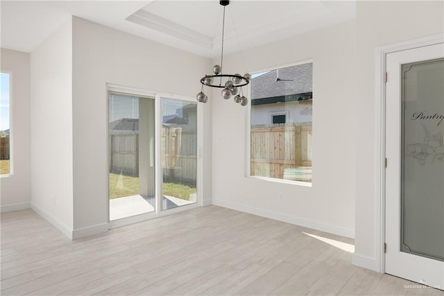 unfurnished dining area featuring a chandelier and light hardwood / wood-style floors