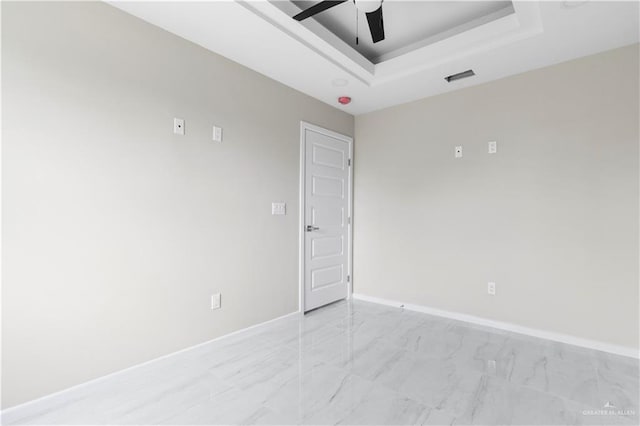 spare room with a raised ceiling and ceiling fan