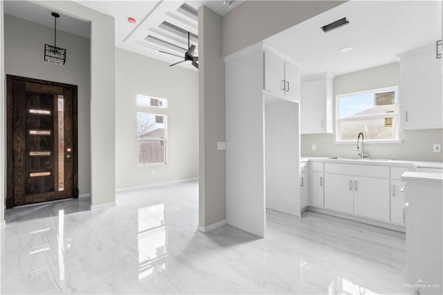 interior space with sink, pendant lighting, white cabinets, and ceiling fan