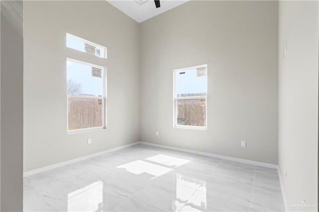 unfurnished room featuring a healthy amount of sunlight and a towering ceiling