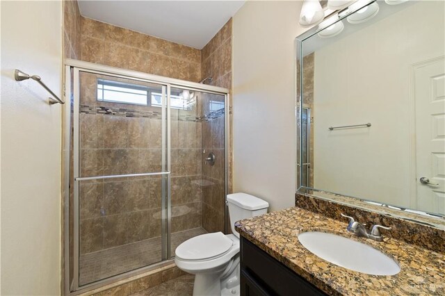 bathroom with a stall shower, toilet, and vanity