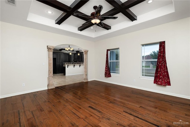 unfurnished room with beamed ceiling, ceiling fan with notable chandelier, hardwood / wood-style flooring, and coffered ceiling