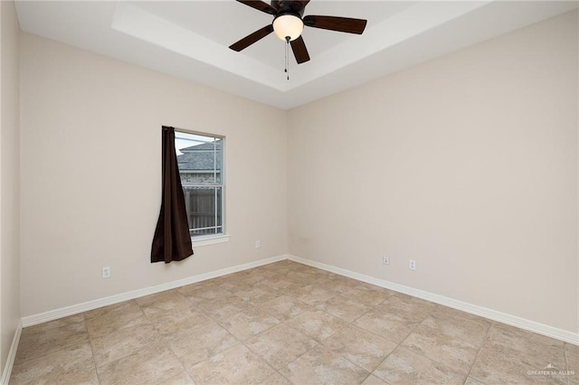 spare room with ceiling fan and a tray ceiling