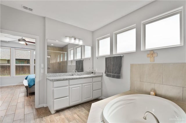 bathroom featuring plus walk in shower, vanity, and ceiling fan