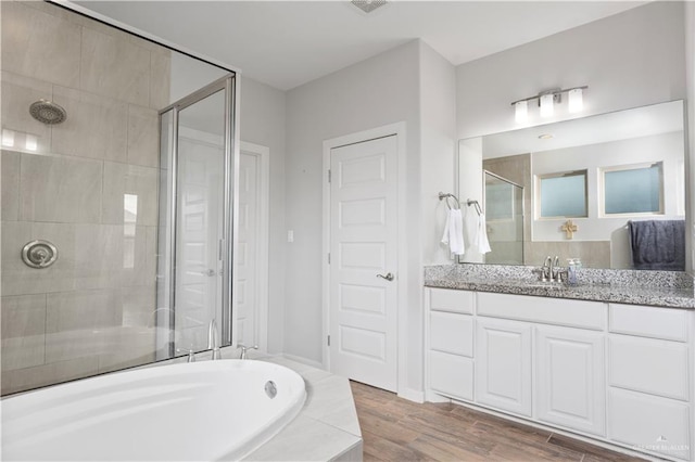 bathroom with hardwood / wood-style floors, vanity, and plus walk in shower