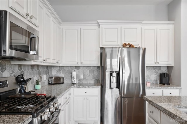 kitchen with decorative backsplash, light stone counters, white cabinetry, and appliances with stainless steel finishes