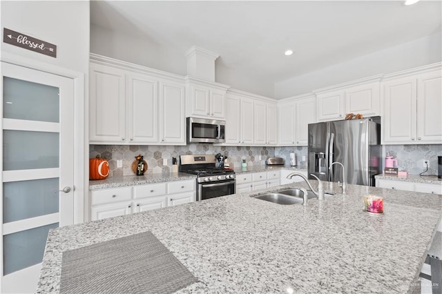 kitchen featuring tasteful backsplash, sink, white cabinets, and stainless steel appliances