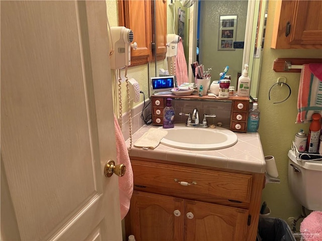 bathroom with backsplash, toilet, and vanity