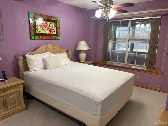 carpeted bedroom featuring ceiling fan and a textured ceiling