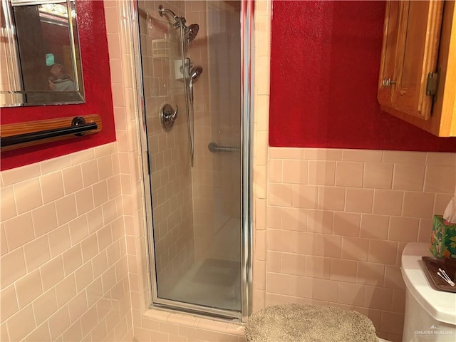 bathroom with toilet, tile walls, and walk in shower