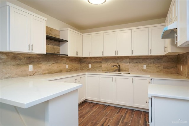 kitchen featuring white cabinets, sink, dark hardwood / wood-style floors, tasteful backsplash, and kitchen peninsula