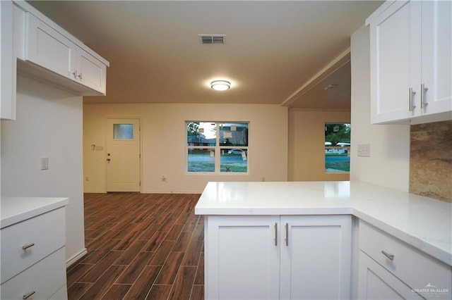 kitchen with white cabinets, dark hardwood / wood-style flooring, and kitchen peninsula