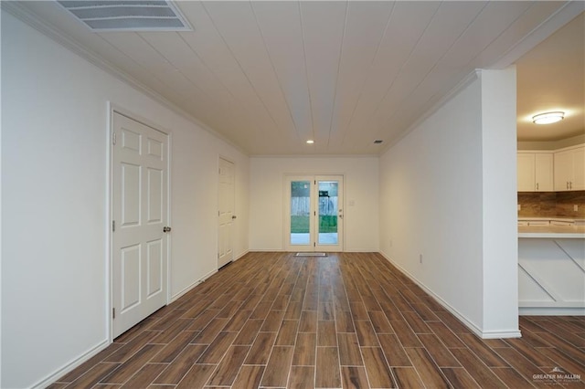 empty room with crown molding and dark wood-type flooring