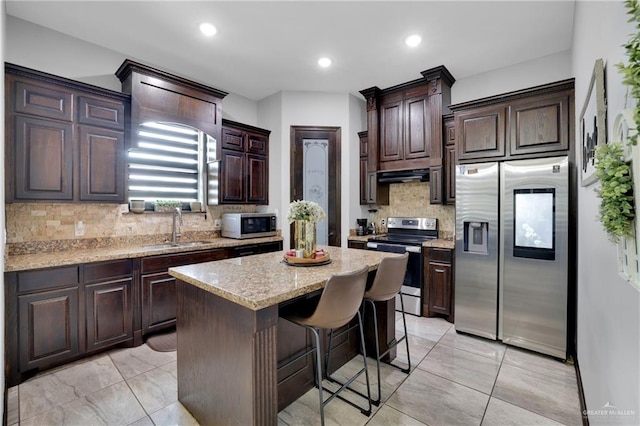 kitchen with a sink, tasteful backsplash, a center island, dark brown cabinetry, and appliances with stainless steel finishes