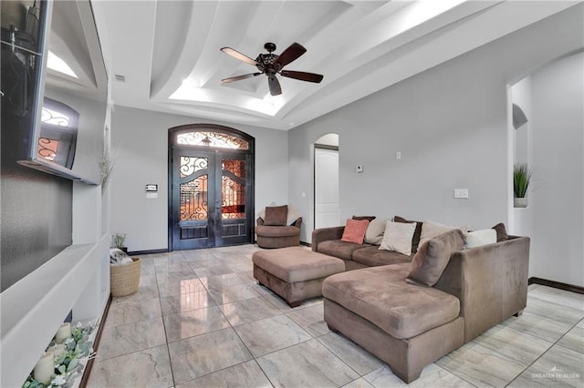 living room featuring arched walkways, a ceiling fan, french doors, and a raised ceiling