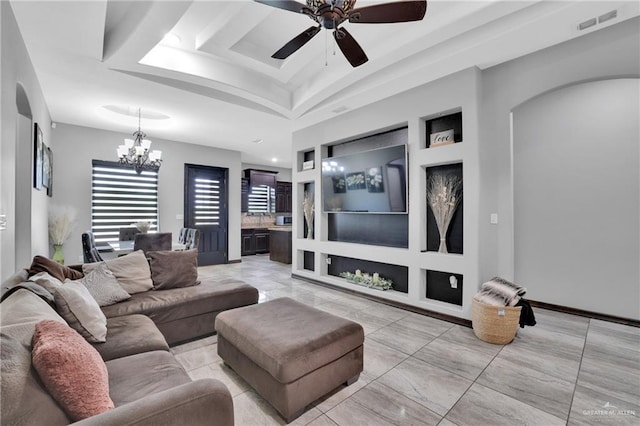 living room with visible vents, arched walkways, ceiling fan with notable chandelier, and a raised ceiling