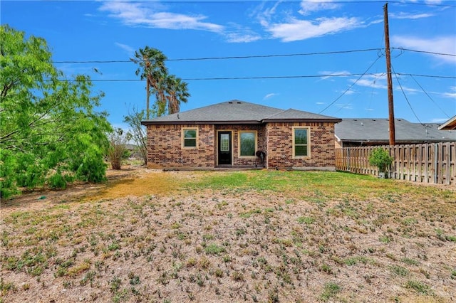 rear view of property featuring fence, a yard, and brick siding
