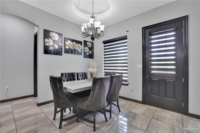 dining area with an inviting chandelier, arched walkways, and baseboards
