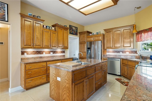 kitchen featuring light tile patterned flooring, light stone counters, stainless steel appliances, and a kitchen island with sink