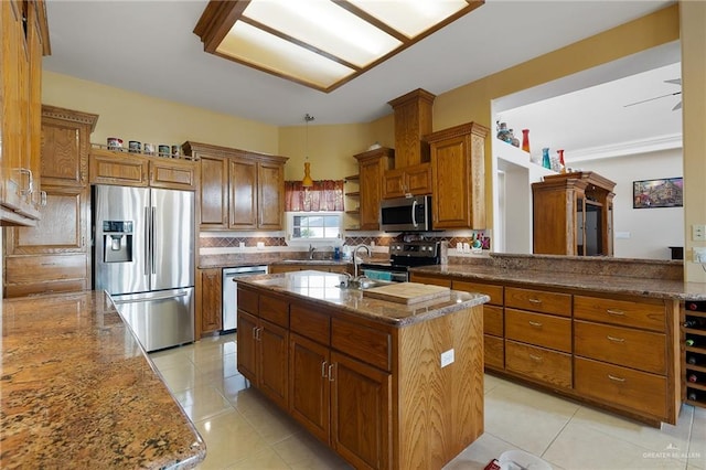 kitchen featuring light tile patterned floors, light stone countertops, stainless steel appliances, and a kitchen island with sink