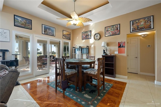 dining area with a tray ceiling, ceiling fan, and light tile patterned flooring