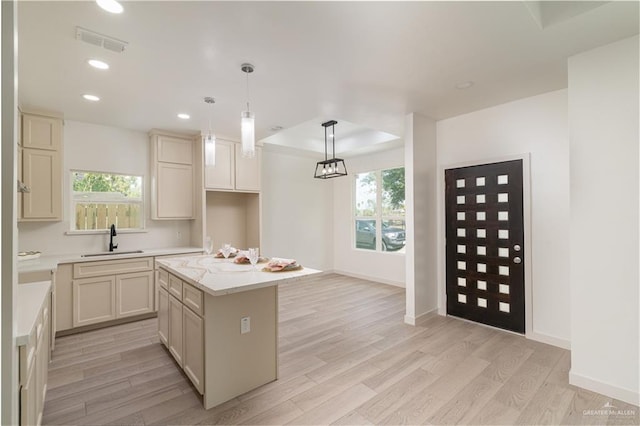 kitchen featuring a wealth of natural light, sink, a center island, hanging light fixtures, and light wood-type flooring