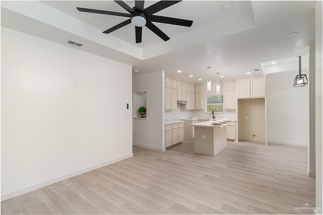 kitchen featuring a tray ceiling, a center island, pendant lighting, and light wood-type flooring