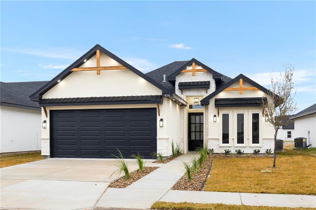 view of front of home featuring a garage, a front yard, and central air condition unit