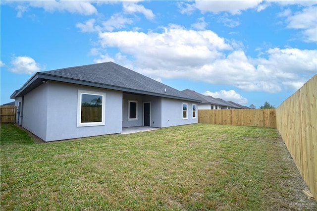 back of property featuring a shingled roof, a fenced backyard, a lawn, and stucco siding