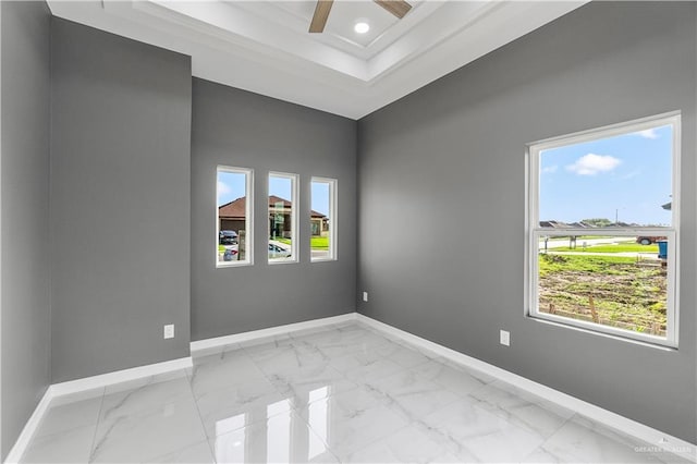 spare room featuring marble finish floor, a ceiling fan, baseboards, and a wealth of natural light