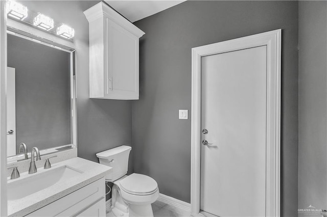 bathroom with toilet, vanity, and baseboards