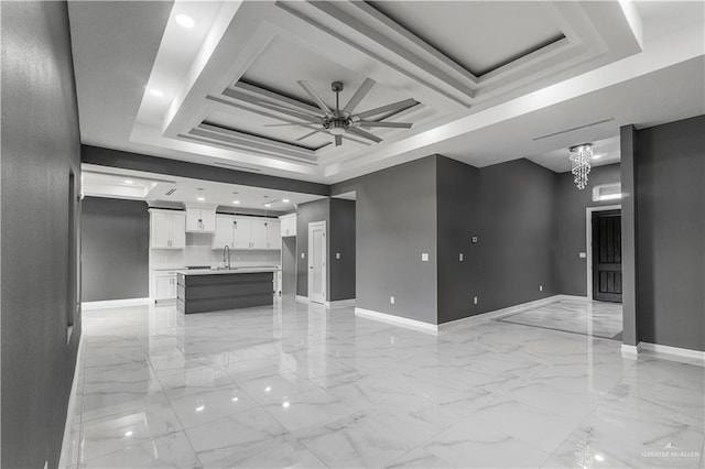 kitchen with light countertops, open floor plan, white cabinetry, an island with sink, and baseboards