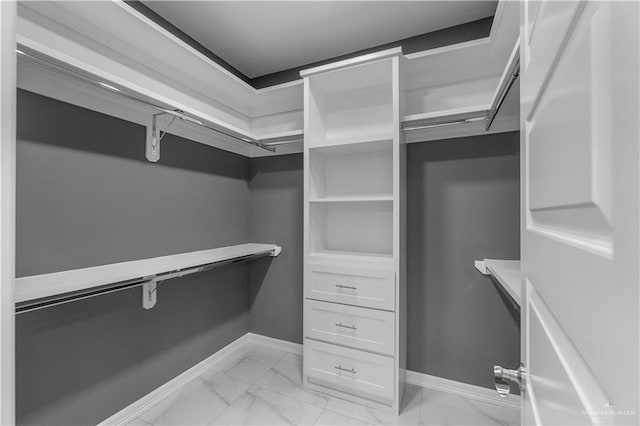 walk in closet featuring marble finish floor