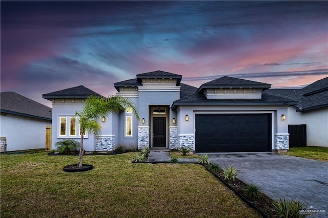 prairie-style home with driveway, a lawn, an attached garage, and stucco siding