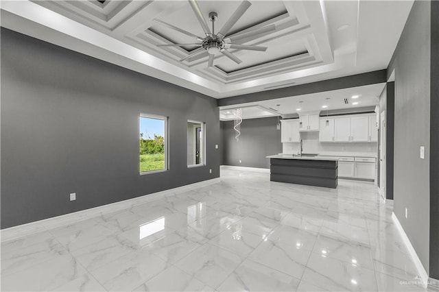 unfurnished living room with baseboards, a raised ceiling, a ceiling fan, marble finish floor, and a sink