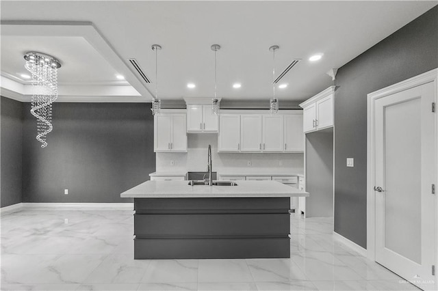 kitchen featuring an island with sink, light countertops, a sink, and hanging light fixtures