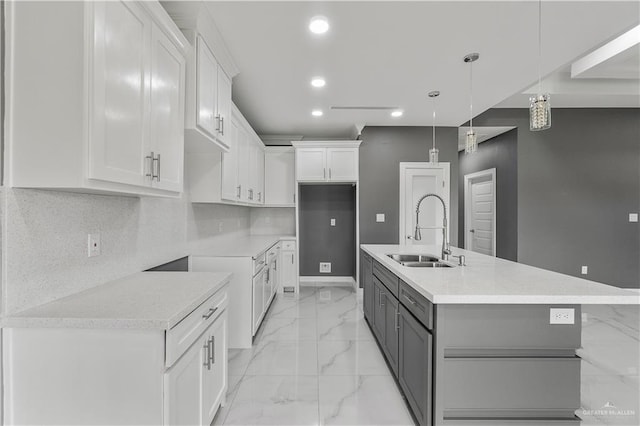 kitchen featuring pendant lighting, white cabinets, and a sink