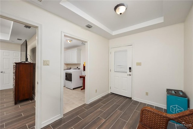 foyer entrance featuring a raised ceiling and washer / clothes dryer