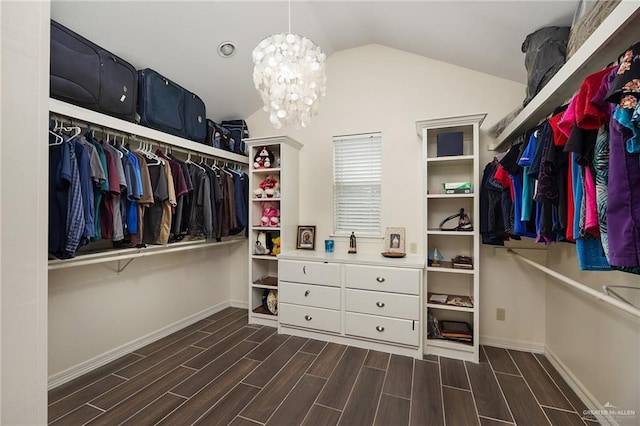 spacious closet with dark wood-type flooring, lofted ceiling, and a notable chandelier