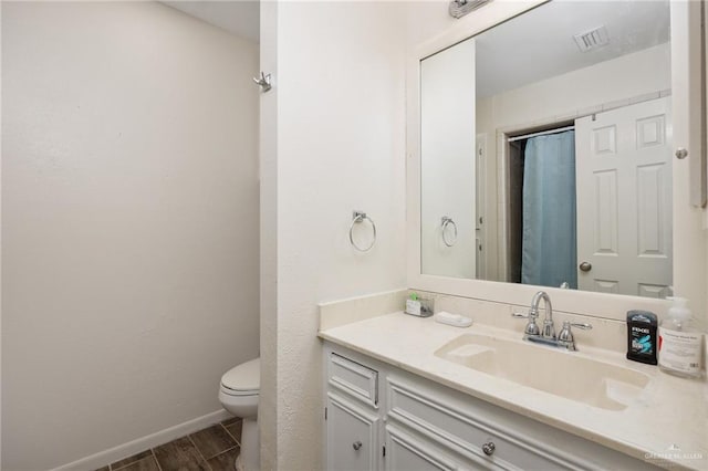 bathroom with hardwood / wood-style flooring, vanity, toilet, and walk in shower