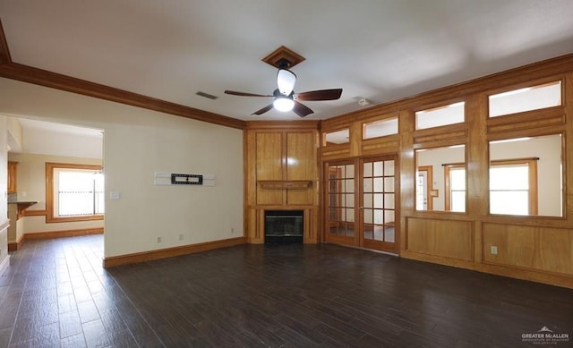 unfurnished living room with a fireplace, dark hardwood / wood-style flooring, ornamental molding, ceiling fan, and french doors