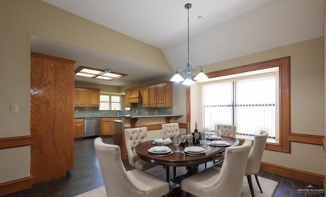 dining area featuring lofted ceiling, dark hardwood / wood-style floors, sink, and a notable chandelier