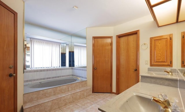 bathroom with tiled tub, vanity, and tile patterned flooring