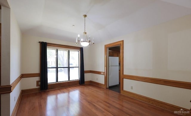 spare room with lofted ceiling, dark hardwood / wood-style flooring, and a notable chandelier