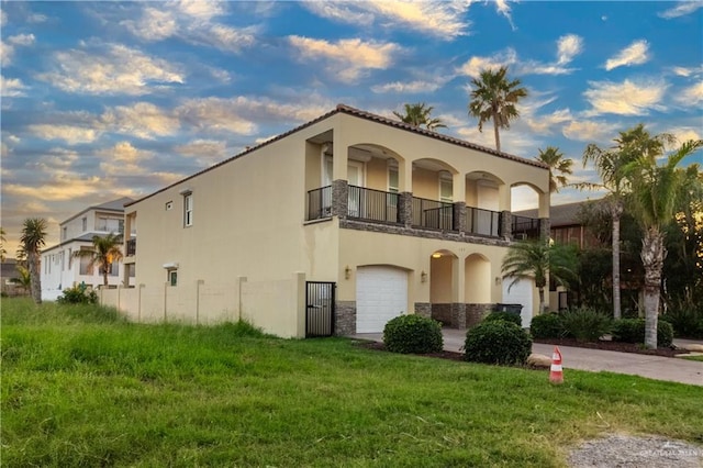 107 E Palm St Unit A, South Padre Island, TX 78597 - view of side of home with a balcony, stucco siding, stone siding, an attached garage, and a yard