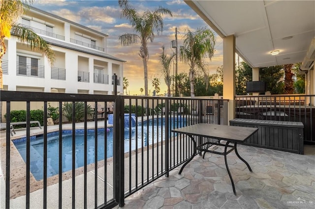 107 E Palm St Unit A, South Padre Island, TX 78597 - balcony at dusk featuring view of pool and a patio