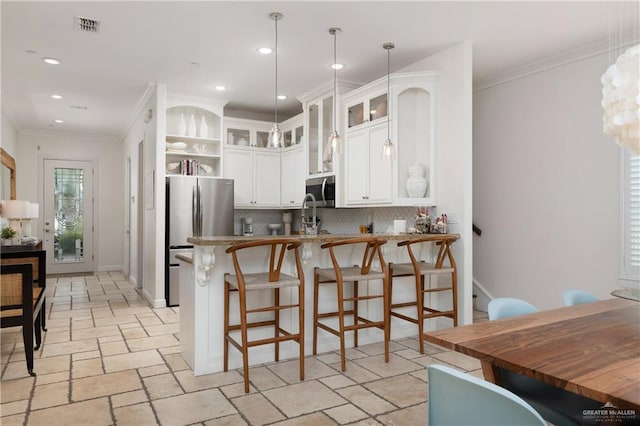 107 E Palm St Unit A, South Padre Island, TX 78597 - kitchen with appliances with stainless steel finishes, stone tile flooring, a peninsula, tasteful backsplash, and a breakfast bar area