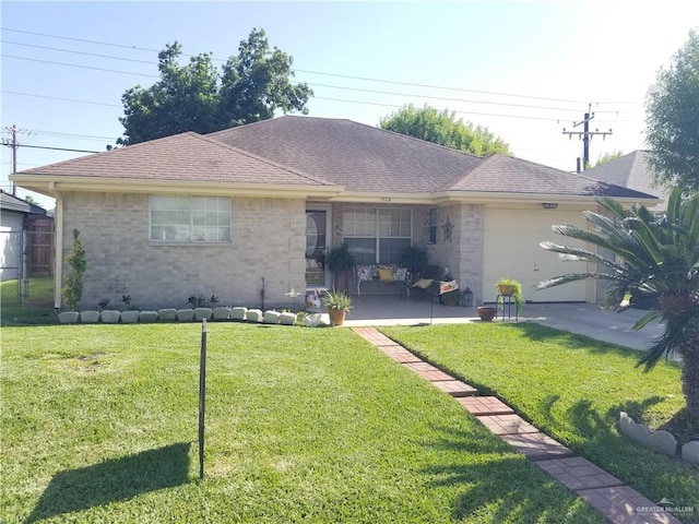 back of property featuring a yard, an attached garage, brick siding, and roof with shingles