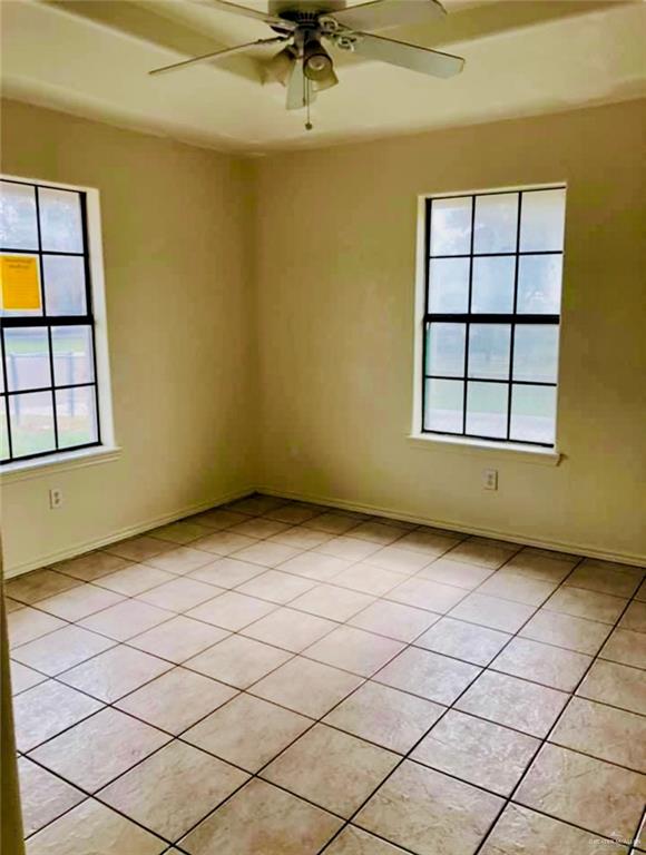 unfurnished room featuring ceiling fan, light tile patterned flooring, and a healthy amount of sunlight